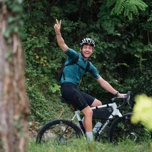 Benji Williams on his bike in the woods, one arm raised