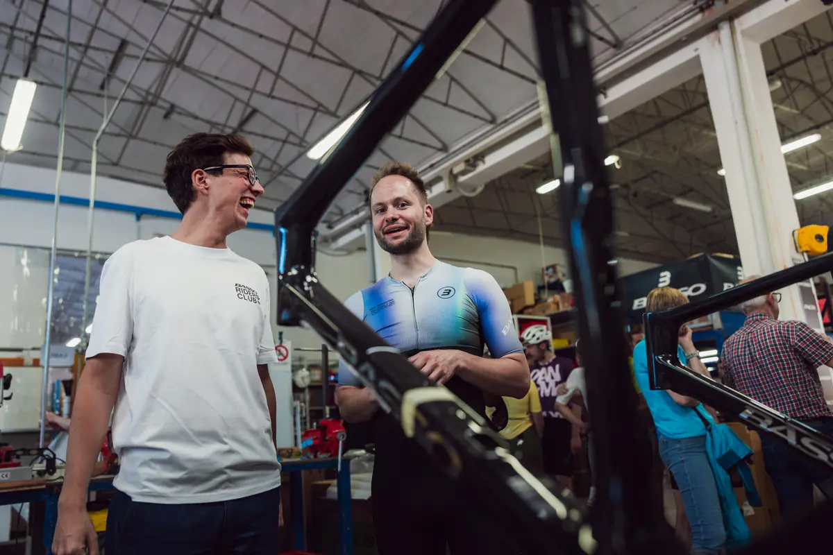 Riders Club members laughing with a Basso frame on the factory floor