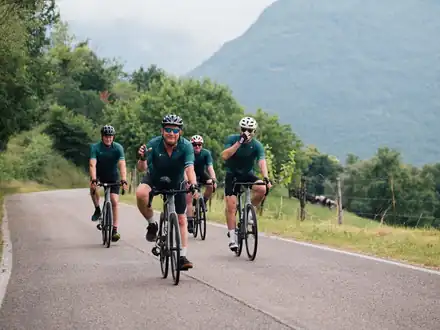 Riders in matching kit on a quiet road below the mountains