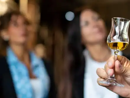 A guest holding up a glass of grappa at a tasting