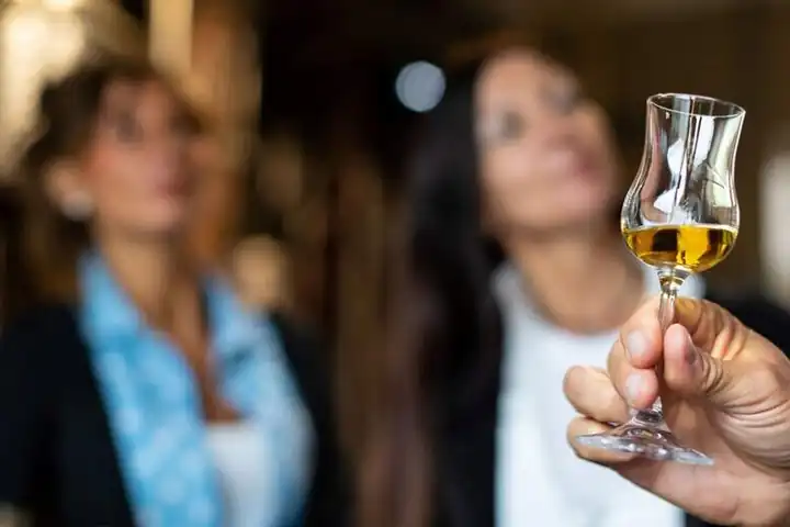 A guest holding up a glass of grappa at a tasting
