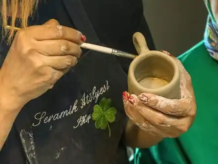 Hands painting a small clay cup