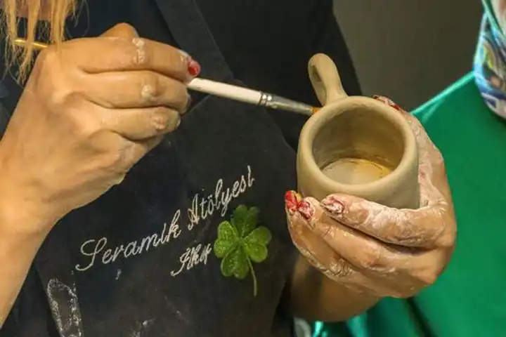 Hands painting a small clay cup