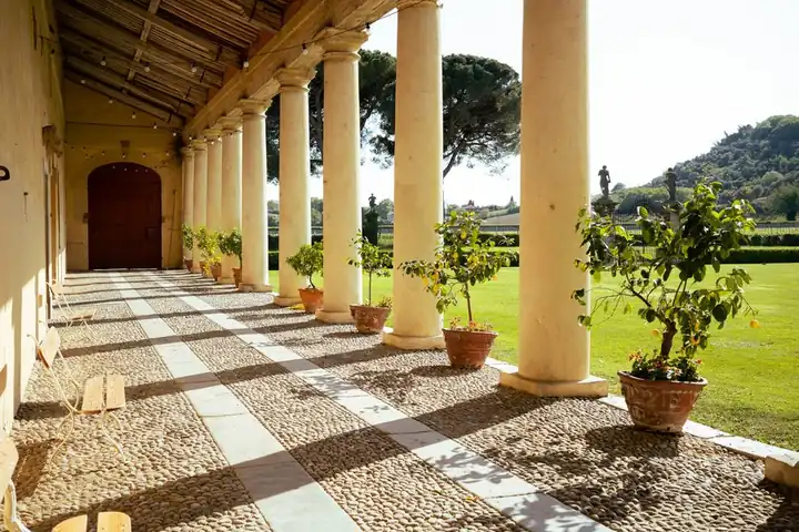 The colonnaded portico of a Palladian villa, with lemon trees in pots along the lawn