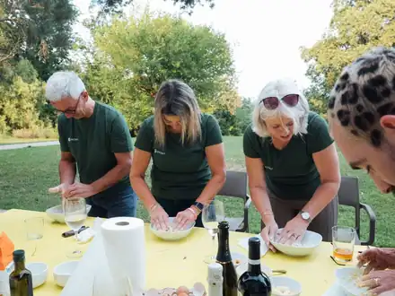 Guests making fresh pasta at a table in a garden