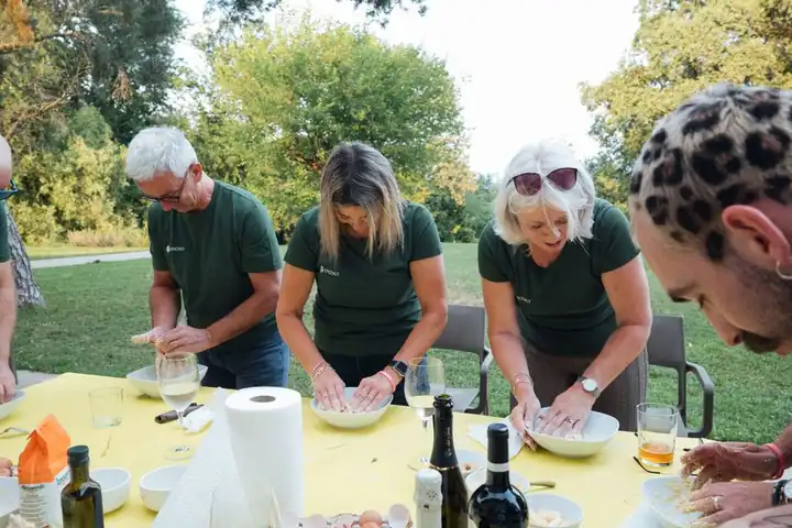 Guests making fresh pasta at a table in a garden