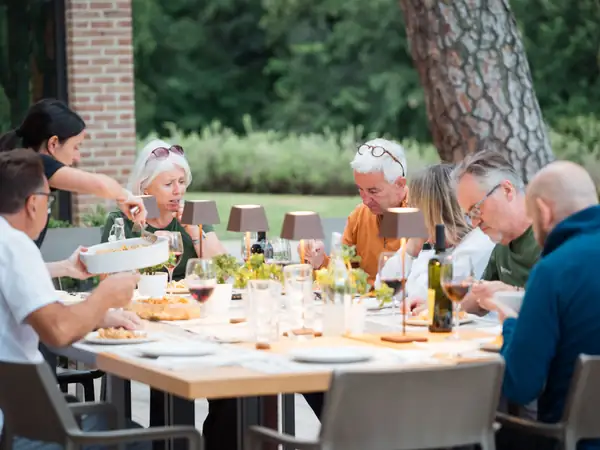 Guests around a long lunch table under the trees