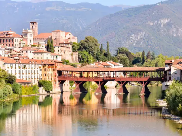 The Ponte degli Alpini and Bassano's old town reflected in the River Brenta at sunset