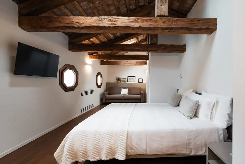 A bedroom at Bassano Club House (BCH) under old wooden beams