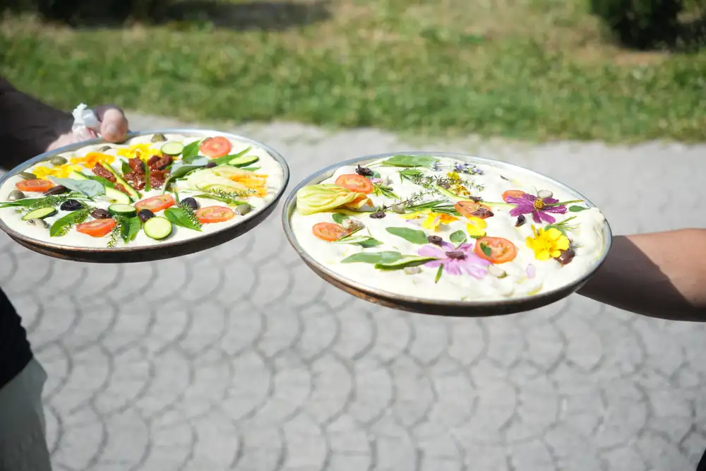 Two focacce decorated with vegetables and edible flowers, ready for the oven