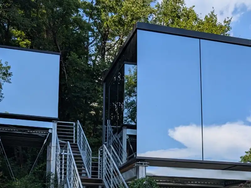 The mirror house at Spino Fiorito, its glass walls reflecting the trees and sky
