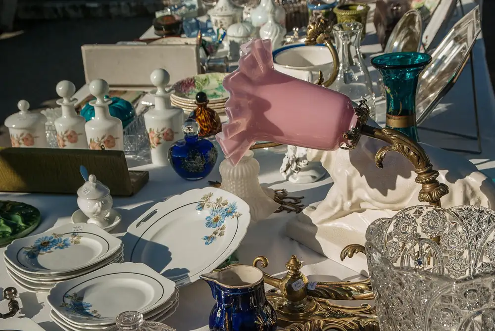 Old china, glassware and a pink lamp on an antique market stall