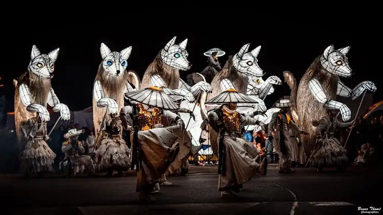 Performers in giant illuminated animal costumes in a night-time street parade