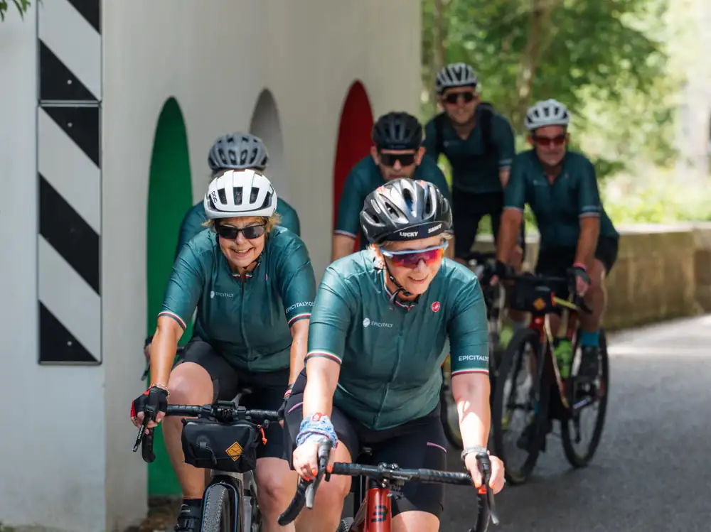 Riders in matching green Epic Italy kit coming through an underpass on a cycle path