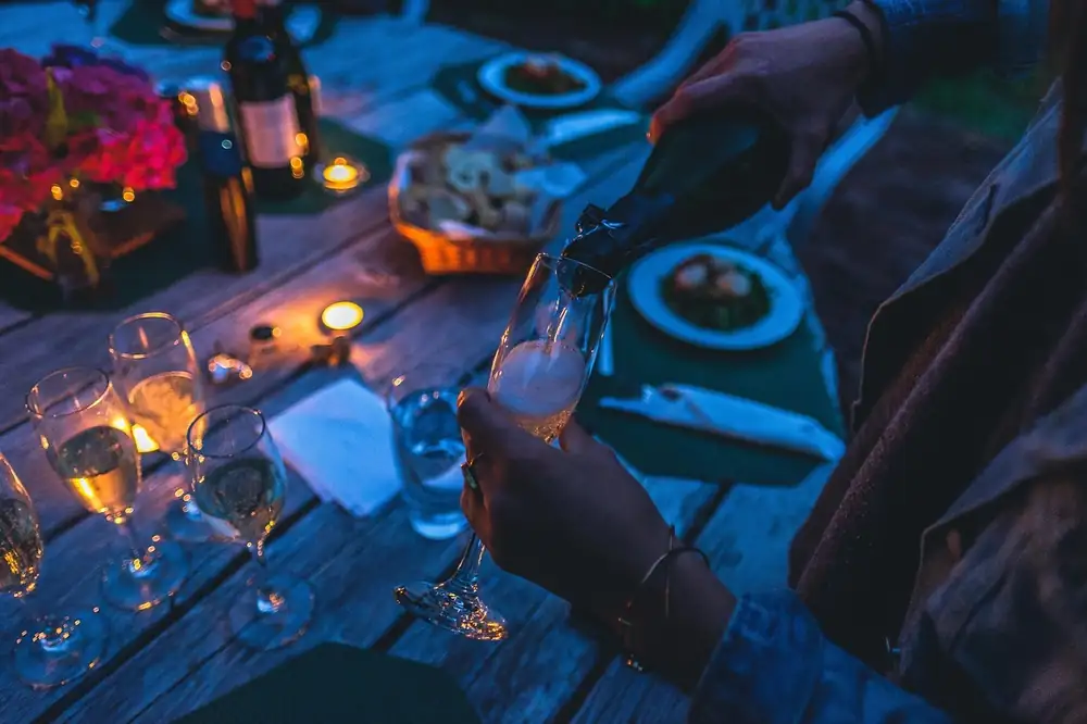 Glasses of wine and small plates on a candlelit table at night