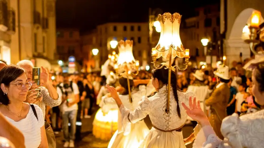 Performers carrying lamps through a crowded street at night