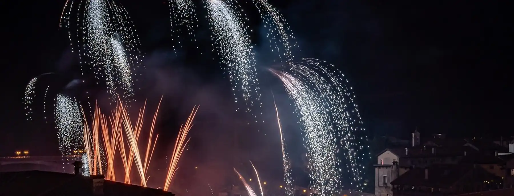Fireworks over the river and the rooftops of Bassano del Grappa at night