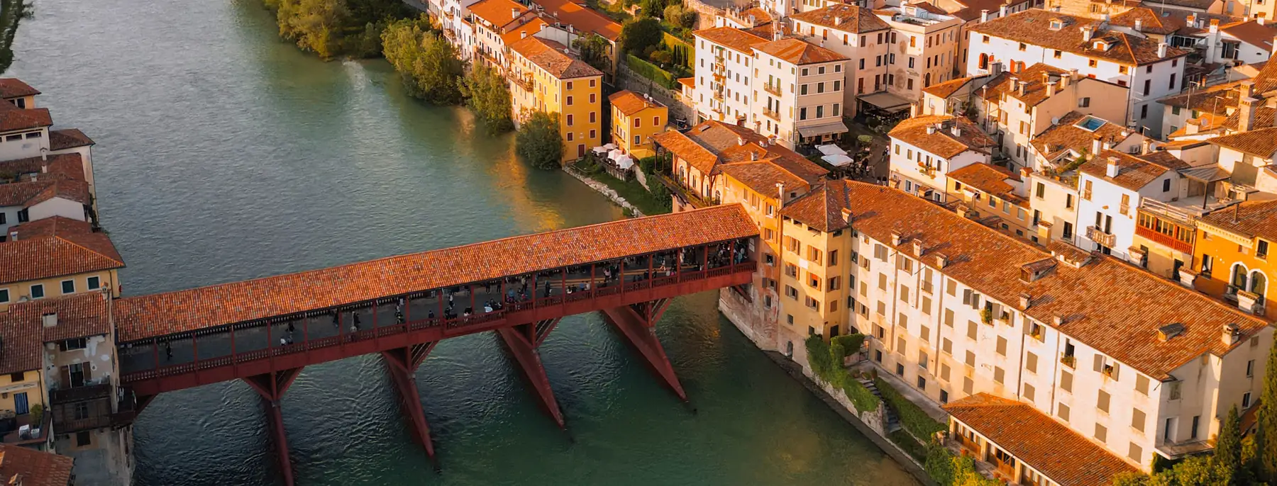 Bassano del Grappa from the air at sunset, the River Brenta running past the old town to the covered Ponte degli Alpini