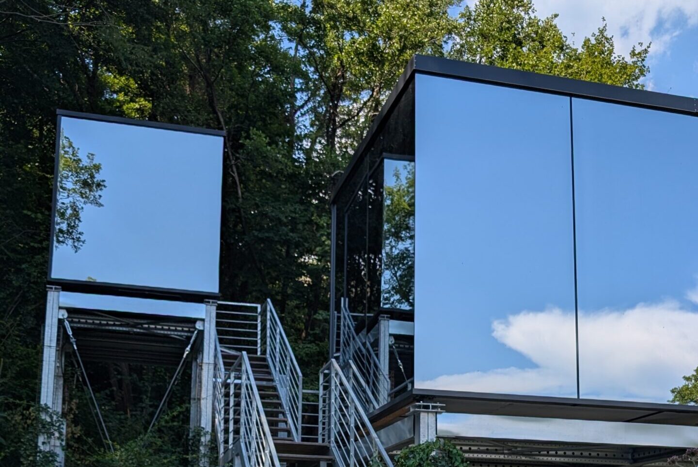The mirror house at Spino Fiorito reflecting the surrounding trees in the hills of Lunigiana